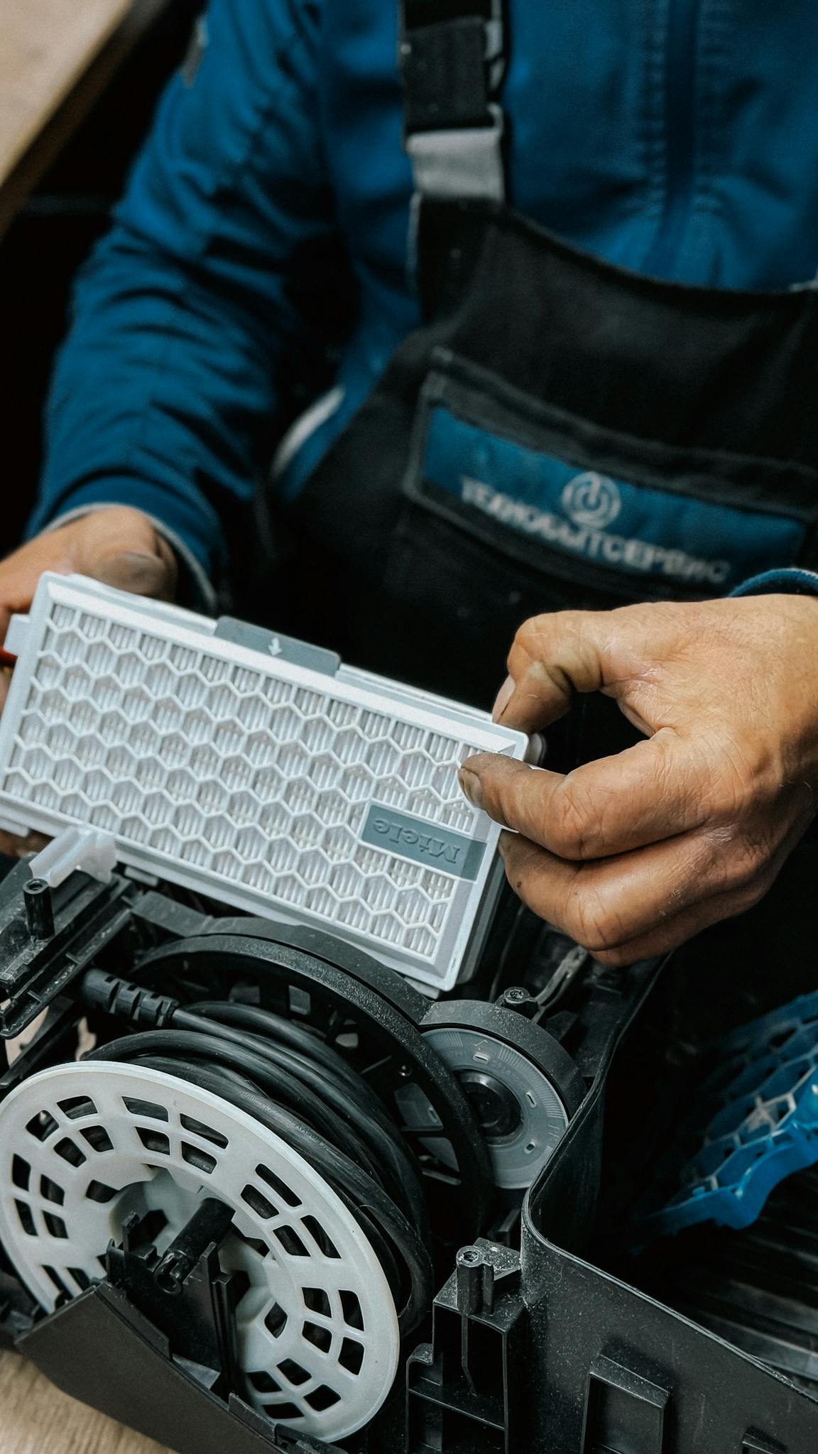 Close-up of a technician handling an air filter during a vacuum cleaner repair.